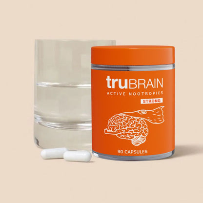 Nootropic capsules in front of a clear glass jar and a glass of water.