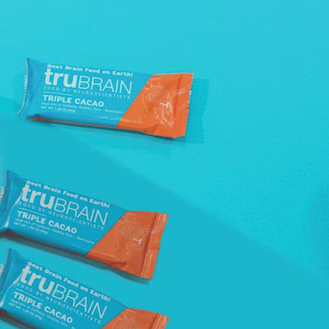Creative professional woman holding a TruBrain Bar while pointing to her forehead to indicate the product is fuleing her brain and breaking brain fog