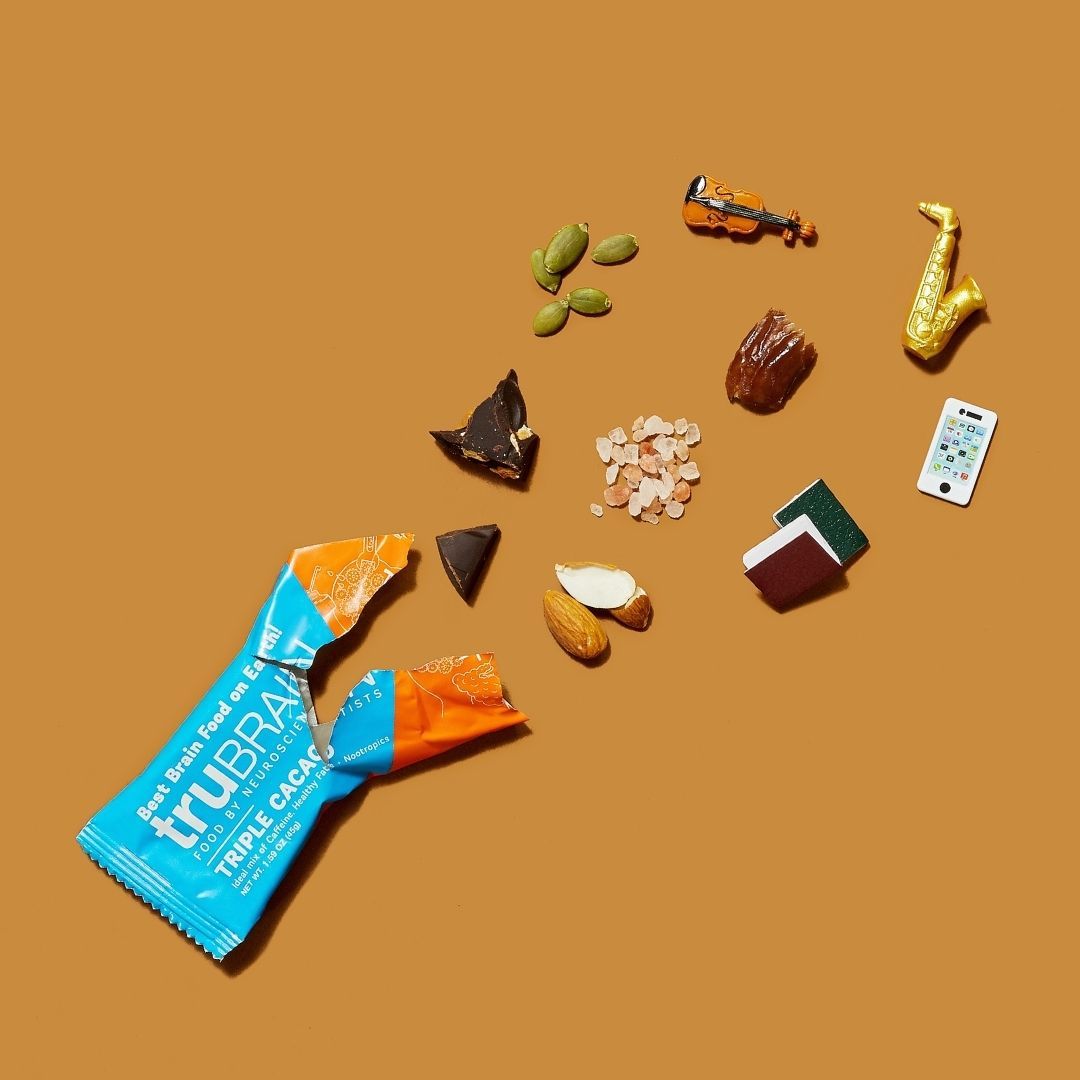 TruBrain’s Bars ripped open on a cocoa background surrounding by mounds of the ingredients in the bar, such as chocolate, peanuts, Nootropics, Healthy fats & Caffeine along with miniature items to represent the benefits.