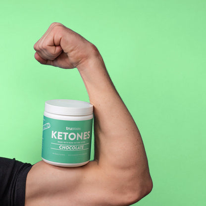 TruBrain Ketones resting on top of a flexed male professional arm to indicate the strength and athletics benefit of TruBrain Ketone Ester
