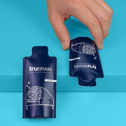 Closeup shot of 2 sleep drinks side by side facing opposite direction while a human hand reaches to grab one for deep sleep